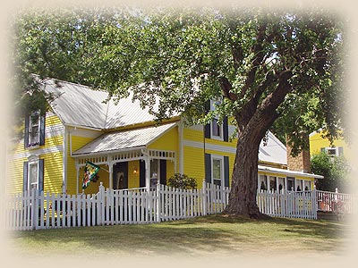Yellow Victorian farmhouse with white picket fence at 1875 Homestead